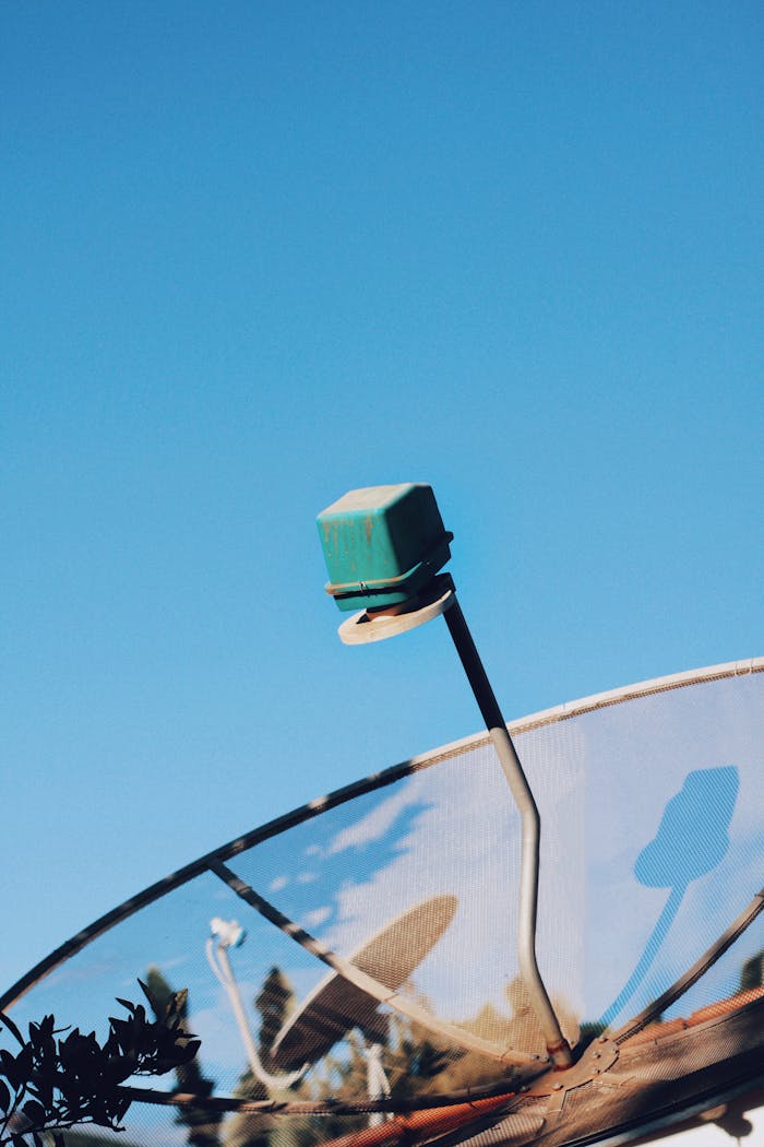 Services-03 Modern satellite dish pointing skyward against a vivid blue sky in Rio Vermelho, Brazil.