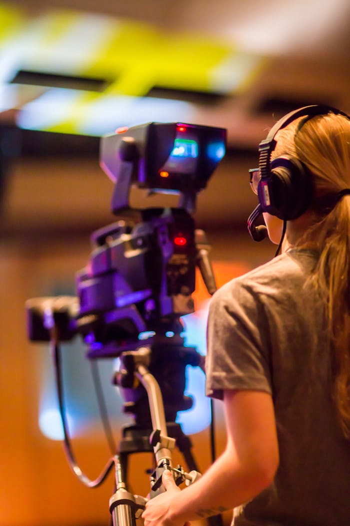 why-choose-us A woman operates a professional camera indoors, focusing on media production.