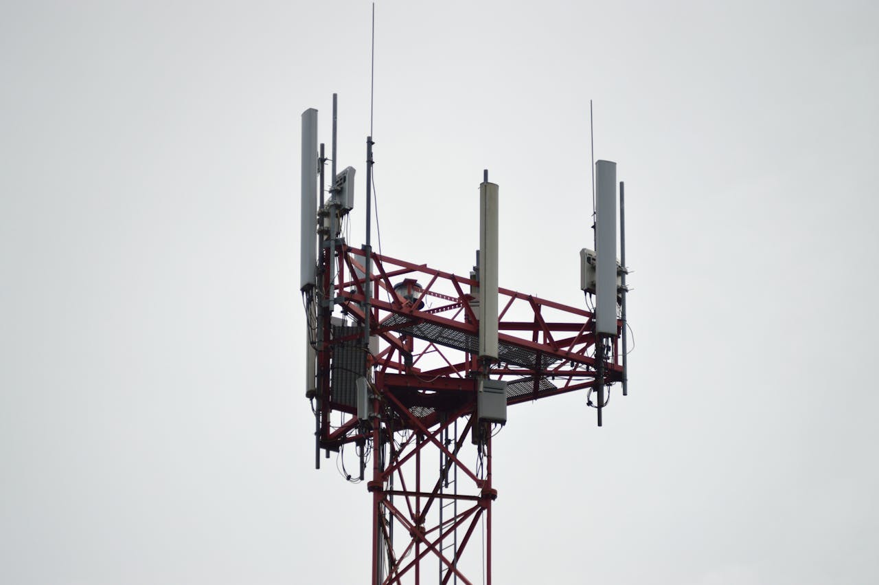 creative-01 A red communication tower with antennas stands tall against a gray sky.